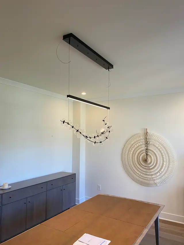 Modern linear pendant fixture installed over a dining room table by Atler Electric